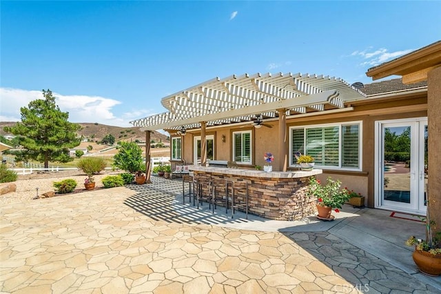 view of patio featuring a pergola, ceiling fan, a mountain view, and exterior bar