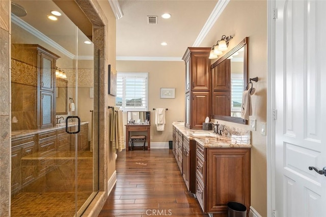 bathroom featuring wood-type flooring, vanity, a shower with door, and ornamental molding