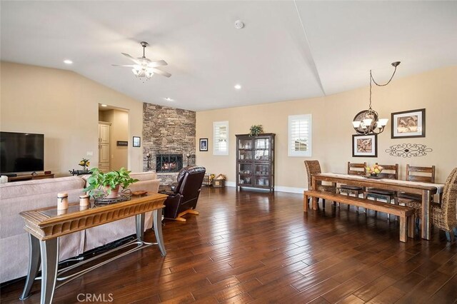 living room featuring lofted ceiling, a fireplace, ceiling fan with notable chandelier, and dark hardwood / wood-style floors