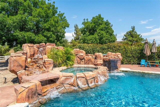 view of swimming pool featuring an in ground hot tub and pool water feature