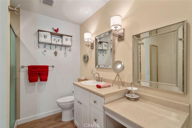 bathroom featuring toilet, vanity, and hardwood / wood-style flooring