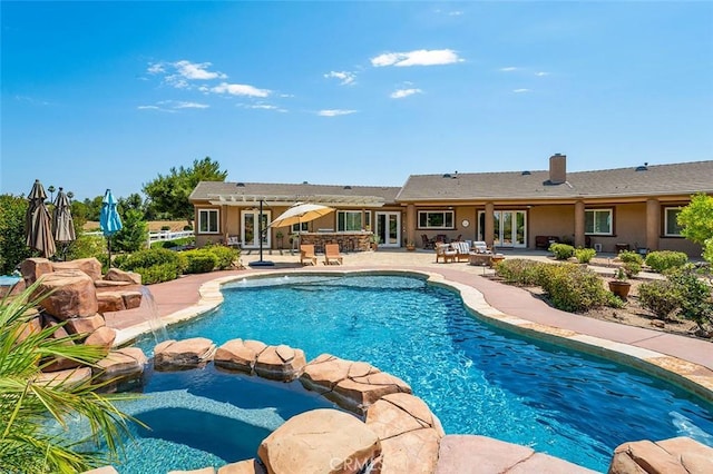 view of pool featuring an in ground hot tub, pool water feature, and a patio