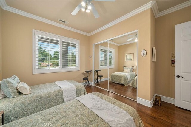 bedroom featuring dark hardwood / wood-style flooring, a closet, ceiling fan, and crown molding