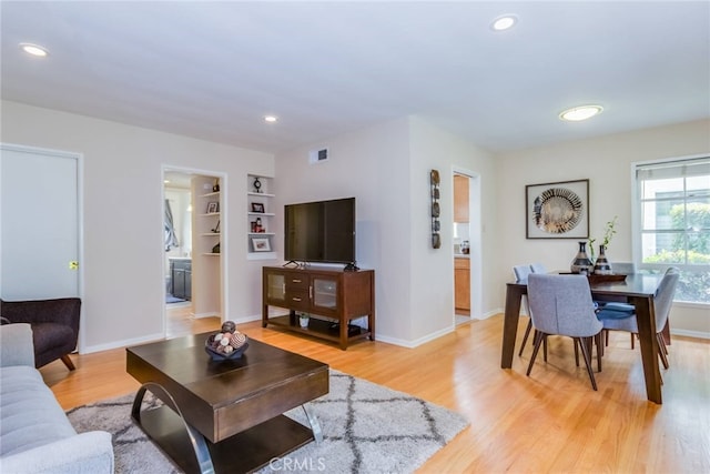 living room with built in features and light wood-type flooring