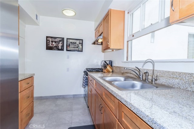 kitchen with sink, appliances with stainless steel finishes, light stone counters, and light tile patterned floors