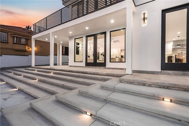 exterior entry at dusk featuring french doors and a patio area