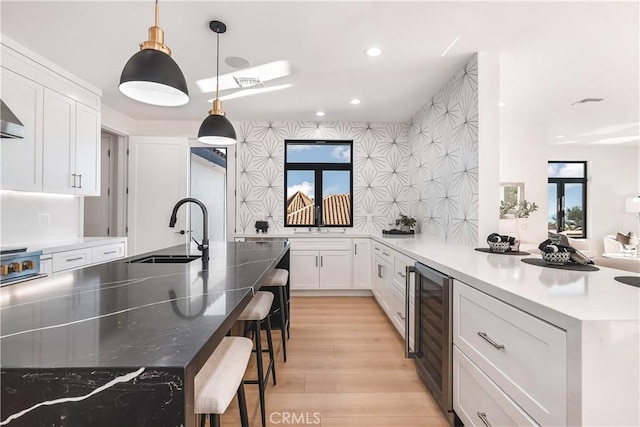 kitchen featuring white cabinetry, beverage cooler, a kitchen breakfast bar, and an island with sink