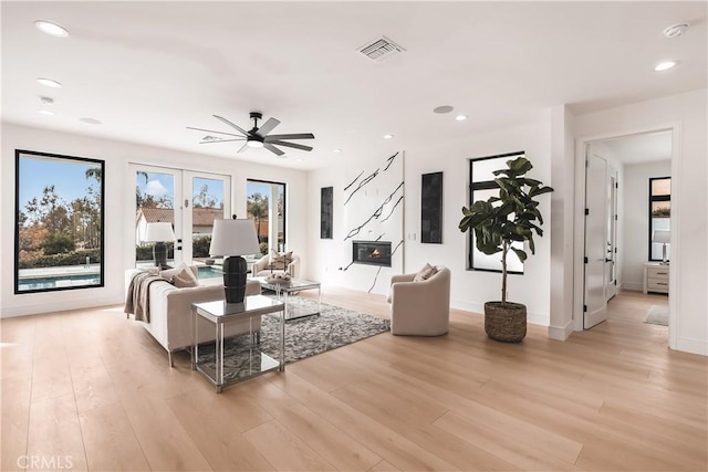 living room with french doors, ceiling fan, and light hardwood / wood-style flooring