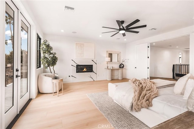 living room featuring french doors, ceiling fan, and light hardwood / wood-style flooring