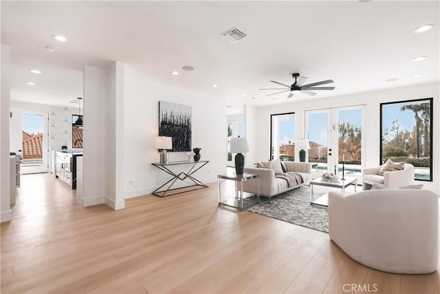 living room featuring ceiling fan, light wood-type flooring, and french doors