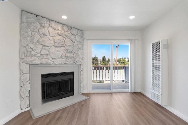 unfurnished living room with hardwood / wood-style floors and a stone fireplace