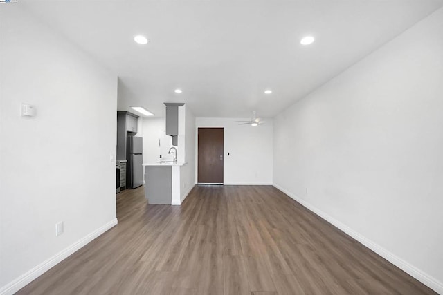 unfurnished living room with ceiling fan, dark hardwood / wood-style flooring, and sink