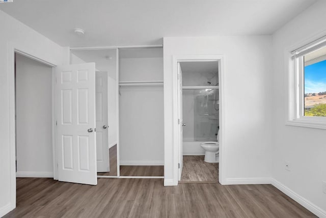 unfurnished bedroom featuring connected bathroom, a closet, and hardwood / wood-style flooring