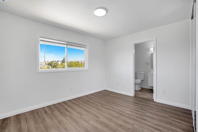 unfurnished bedroom featuring wood-type flooring and ensuite bath