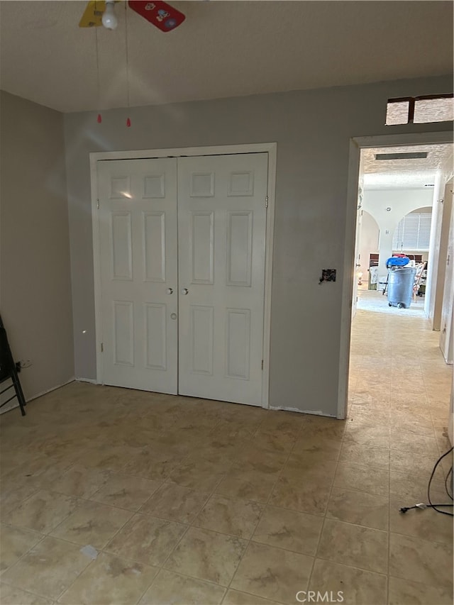 unfurnished bedroom with ceiling fan and a closet