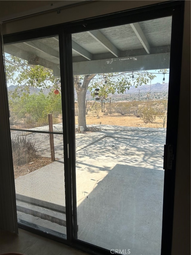 doorway with a wealth of natural light, beam ceiling, and concrete flooring