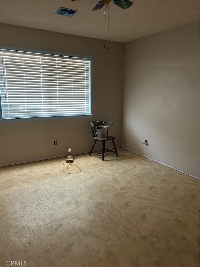 empty room featuring a textured ceiling and ceiling fan