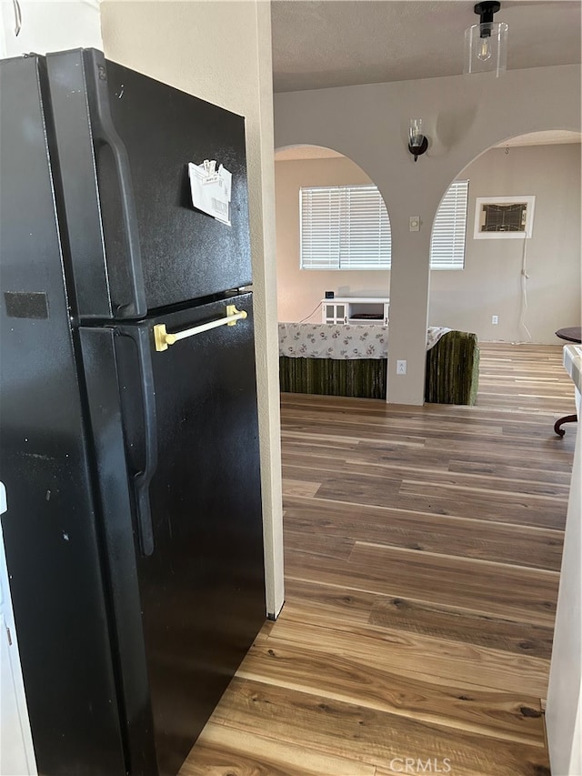 kitchen featuring a textured ceiling, wood-type flooring, and black fridge