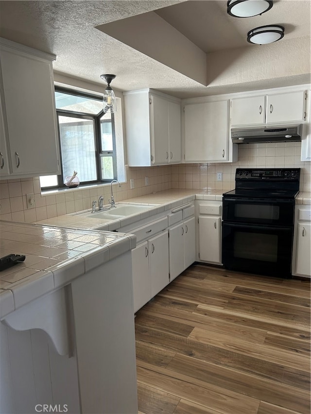 kitchen featuring tile countertops, dark hardwood / wood-style floors, white cabinets, and black range with electric cooktop