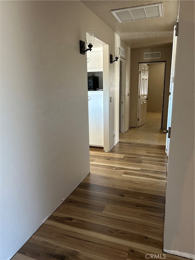 hallway featuring hardwood / wood-style flooring and a textured ceiling