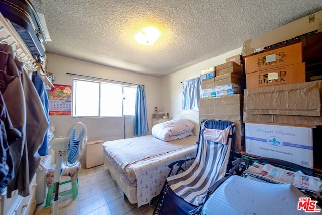 tiled bedroom featuring a textured ceiling