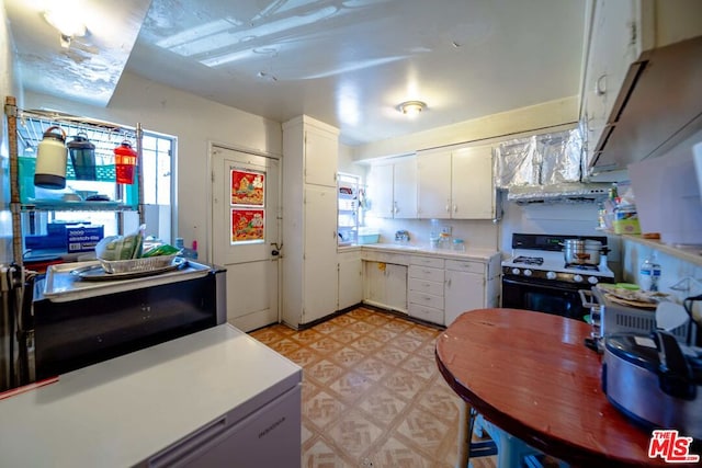 kitchen featuring gas range gas stove, white cabinets, fridge, light tile patterned floors, and ventilation hood