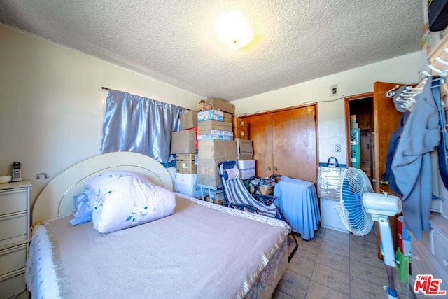 bedroom with a closet, tile patterned floors, and a textured ceiling