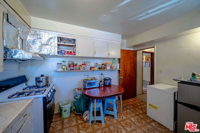 kitchen featuring white cabinetry, white range with gas cooktop, and light tile patterned floors