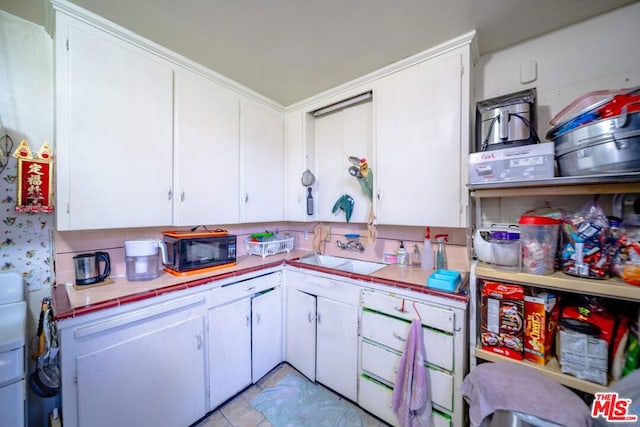 kitchen with sink, light tile patterned flooring, white cabinets, and backsplash