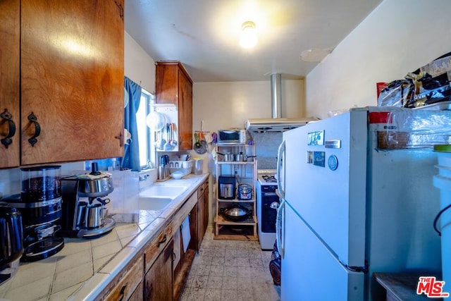 kitchen with sink, tile countertops, light tile patterned floors, and white appliances