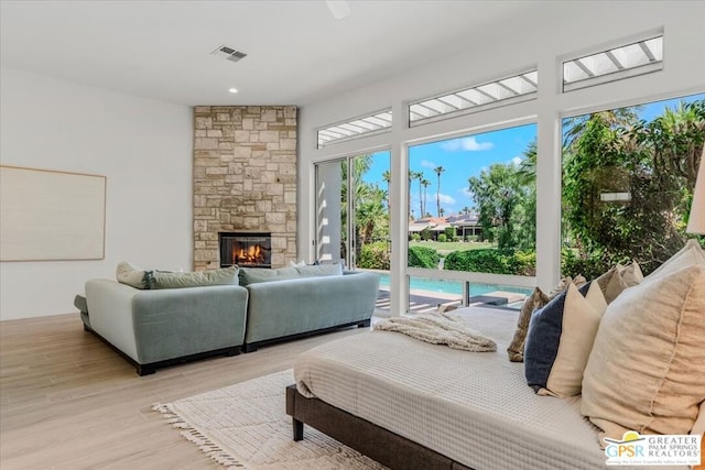 living room with a stone fireplace and light wood-type flooring