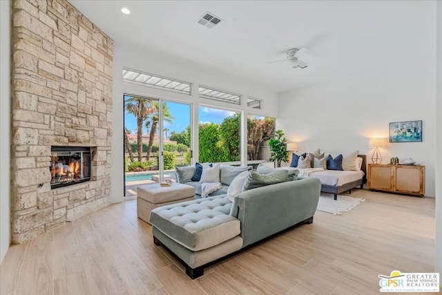 living room featuring ceiling fan, a fireplace, and light wood-type flooring