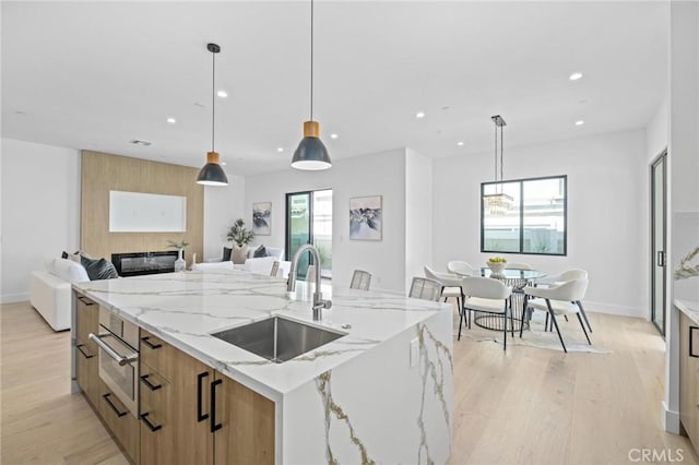 kitchen with a healthy amount of sunlight, decorative light fixtures, a large island, and sink