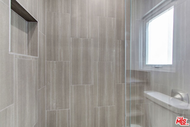 bathroom with tile walls, a shower with shower door, and toilet