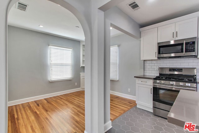 kitchen featuring white cabinetry, stainless steel appliances, tile patterned floors, and tasteful backsplash