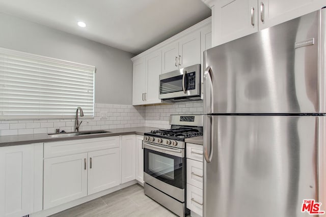 kitchen with white cabinetry, tasteful backsplash, light tile patterned floors, appliances with stainless steel finishes, and sink