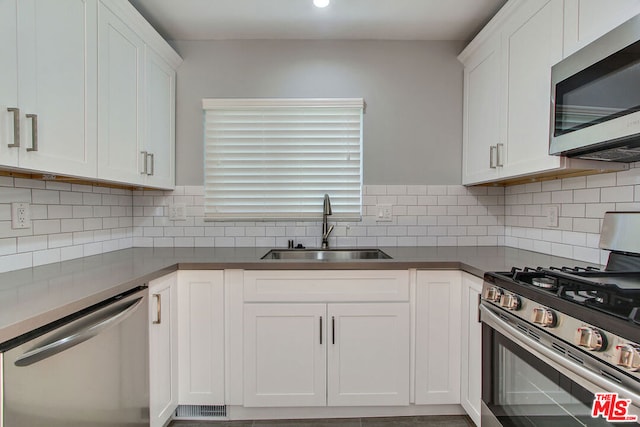 kitchen featuring appliances with stainless steel finishes, white cabinetry, tasteful backsplash, and sink