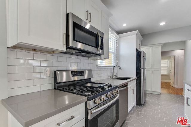 kitchen featuring stainless steel appliances, white cabinets, sink, decorative backsplash, and wood-type flooring