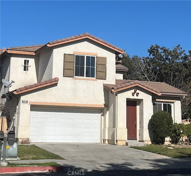 mediterranean / spanish-style home with a tiled roof, concrete driveway, an attached garage, and stucco siding