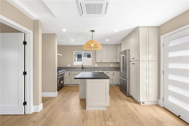 kitchen with pendant lighting, sink, a kitchen island, appliances with stainless steel finishes, and light wood-type flooring