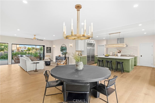 dining area with ceiling fan with notable chandelier and light wood-type flooring