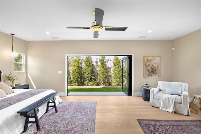 bedroom with ceiling fan, hardwood / wood-style flooring, access to outside, and multiple windows