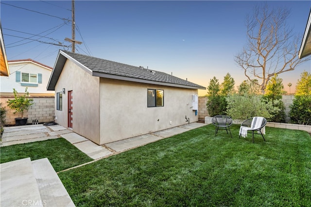 back house at dusk with a yard and a patio area