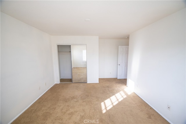 unfurnished bedroom featuring light carpet and a closet