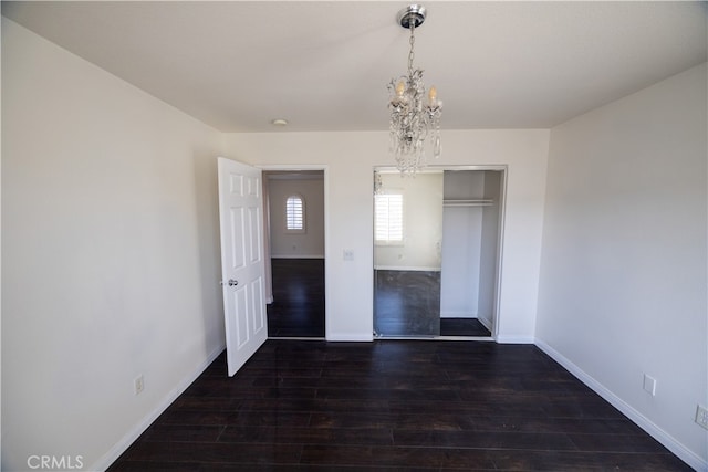 unfurnished bedroom featuring a notable chandelier, dark hardwood / wood-style flooring, and a closet