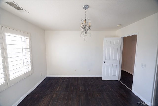 spare room featuring a chandelier and wood-type flooring