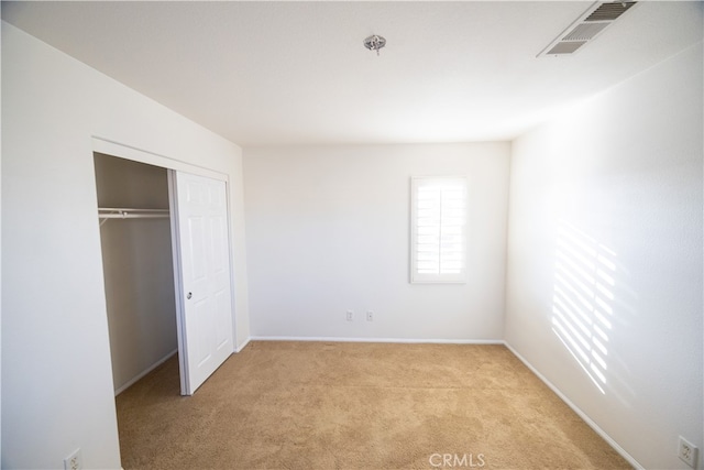 unfurnished bedroom featuring a closet and light colored carpet