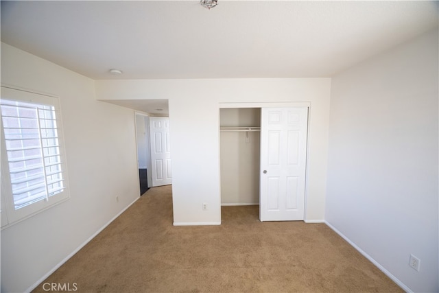 unfurnished bedroom featuring multiple windows, light carpet, and a closet