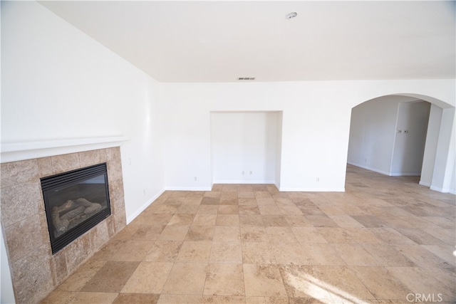 unfurnished living room with a tile fireplace and light tile patterned floors