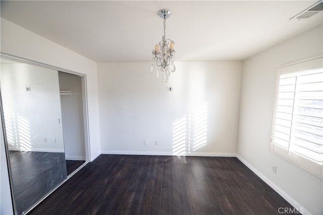 unfurnished bedroom featuring hardwood / wood-style flooring, a closet, and a chandelier